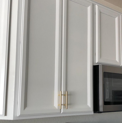 Cosmas 305-4BB Brushed Brass Euro Style Bar Pull on white shaker cabinets