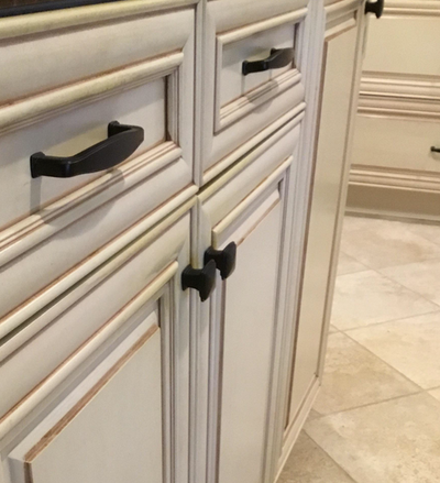 beige kitchen cabinet with a black Cosmas 4392FB pulls and two square cabinet knobs in the flat black finish. 