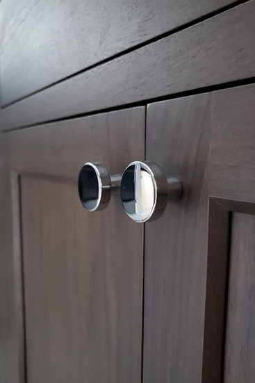 A pair of Cosmas 5234CH polished chrome cabinet knob on dark wood cabinet