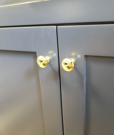 Cosmas 5305PB Polished Brass Round Cabinet Knob on a blue kitchen cabinet