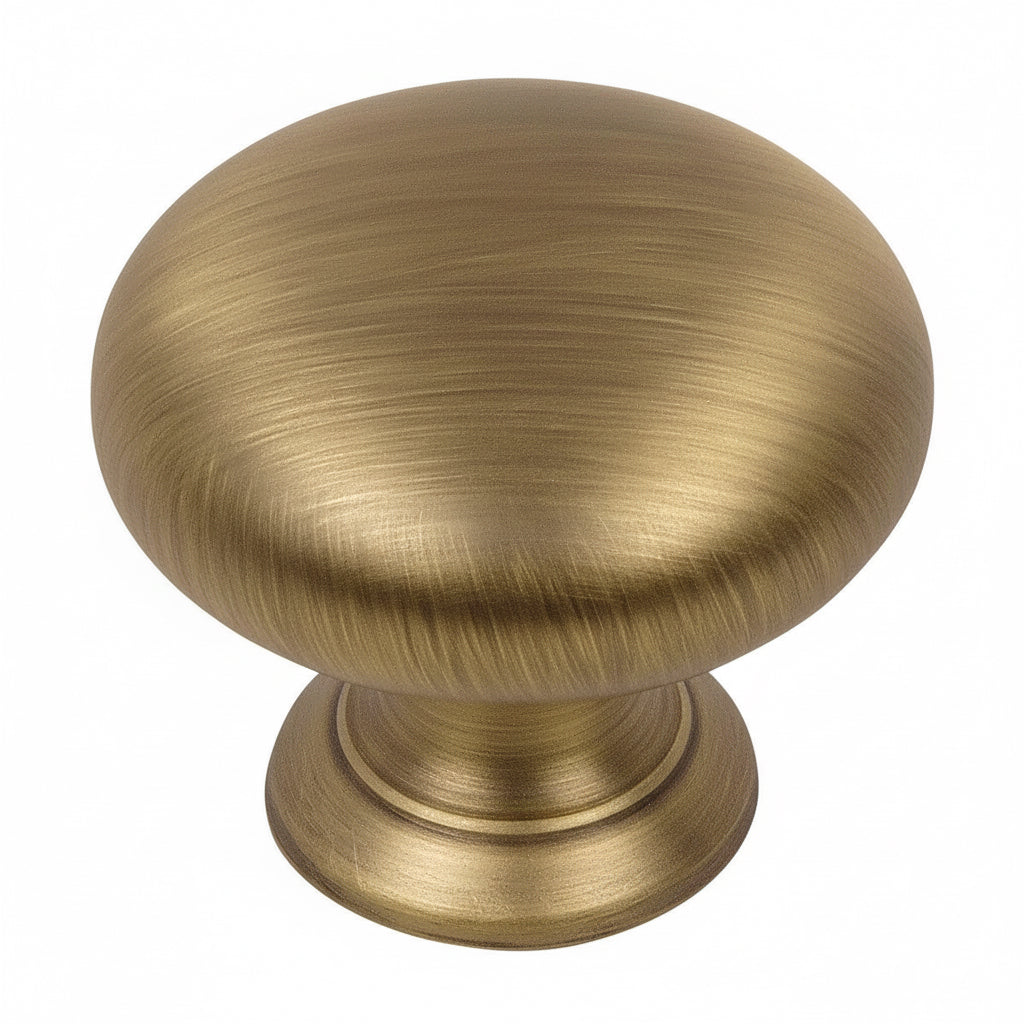 Round cabinet knob in brushed antique brass finish with one and a quarter inch diameter