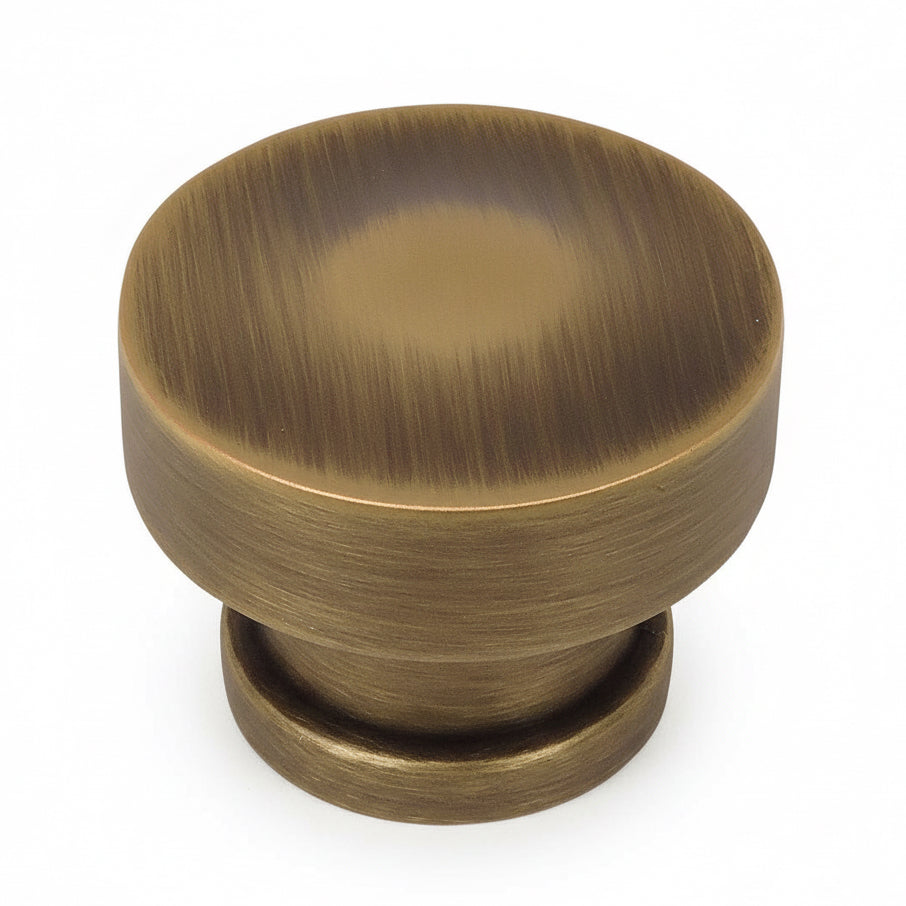 Round rigid cabinet knob in brushed antique brass finish with one and a quarter inch diameter