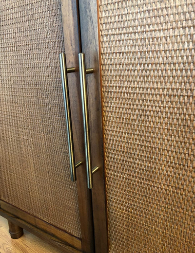 Antique brass handles on a wooden cabinet with wicker doors