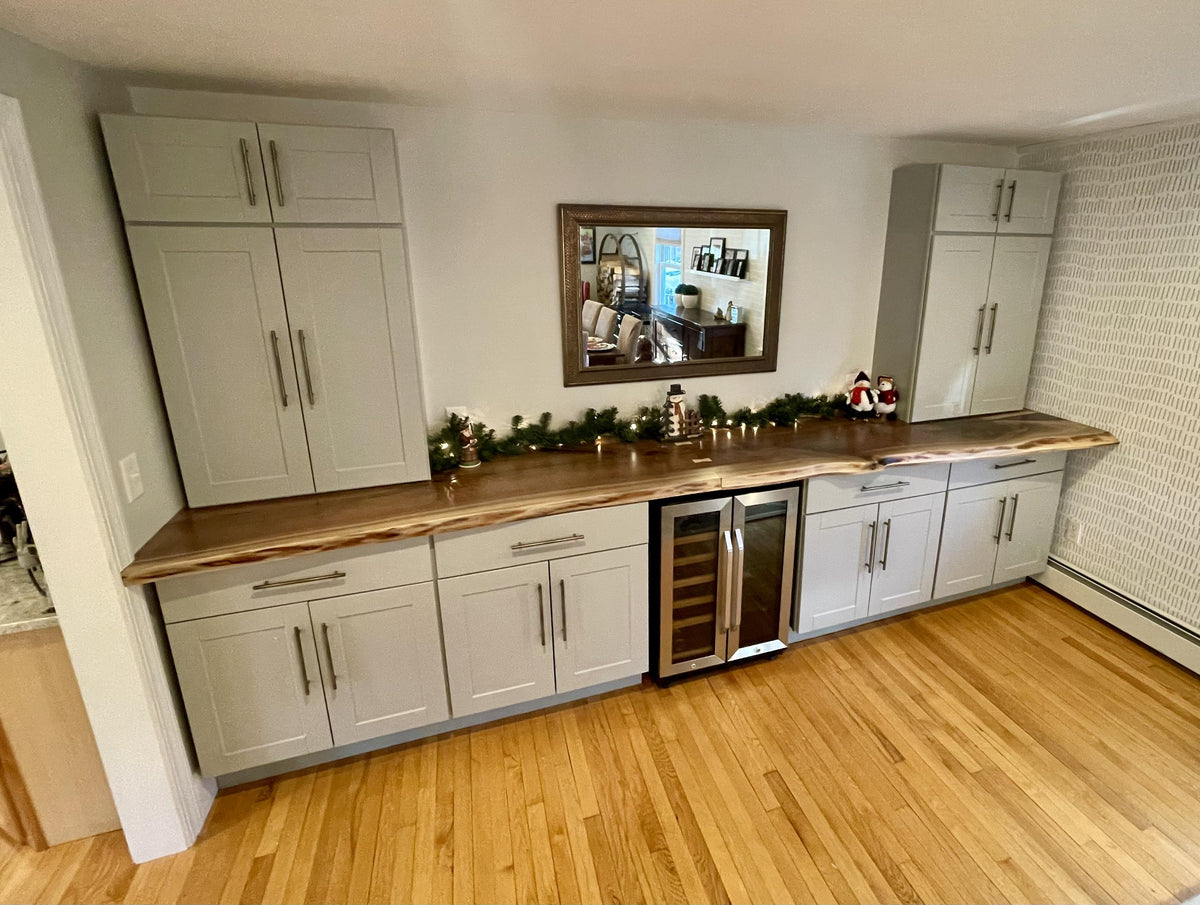 antique brass handles on gray kitchen cabinets with a wood countertop.