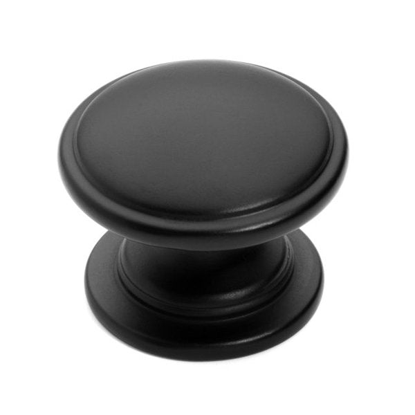 Round furniture knob in flat black finish with slightly raised center and one and a quarter inch diameter